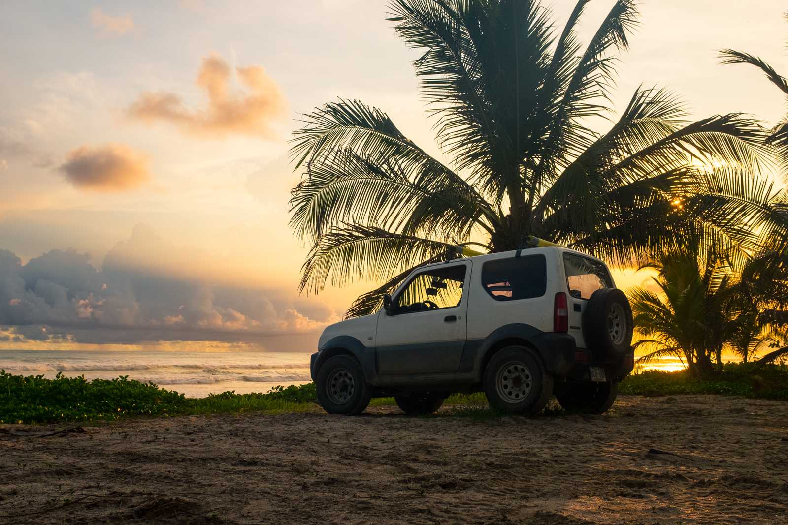 A suzuki car parked in front of the beach at sunset